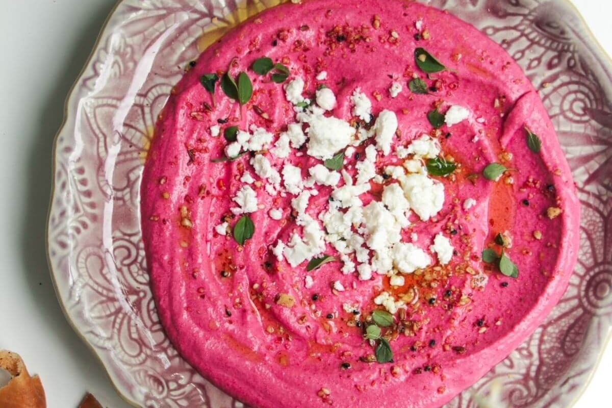 Beet hummus recipe on a plate with feta cheese.