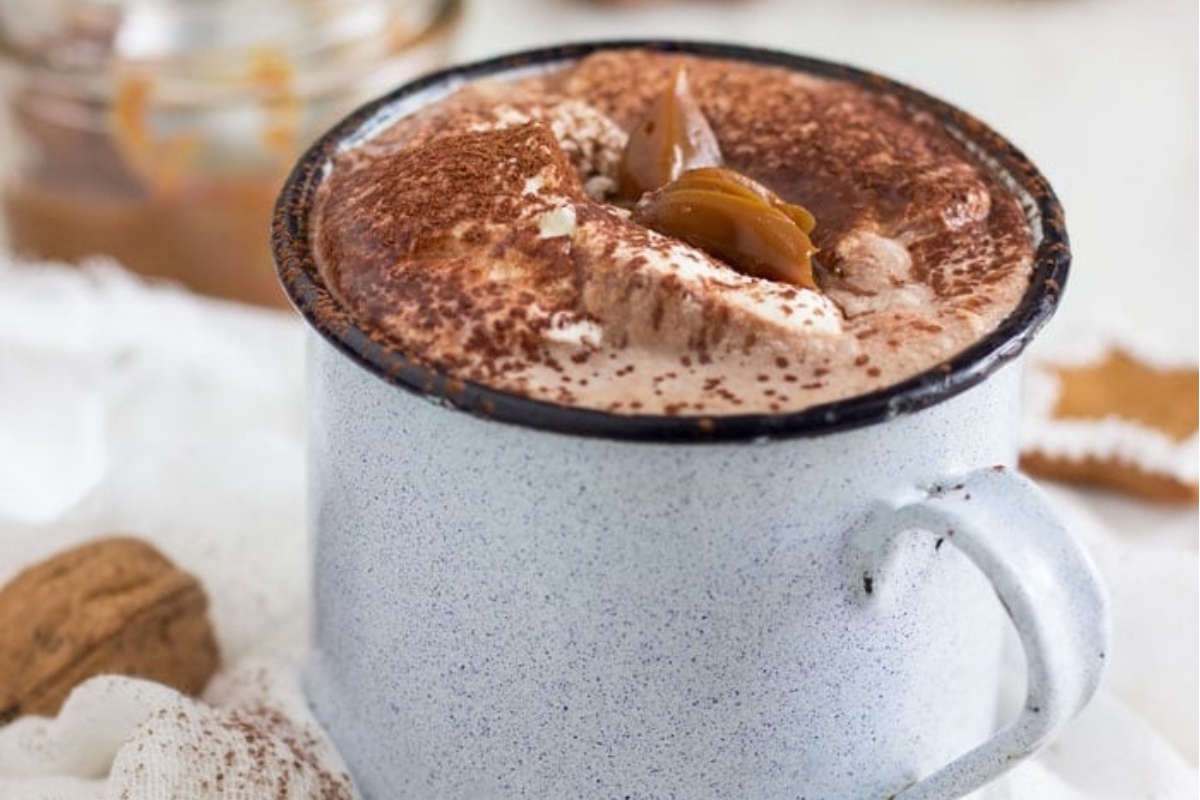 A cup of hot cocoa with caramel and nuts.