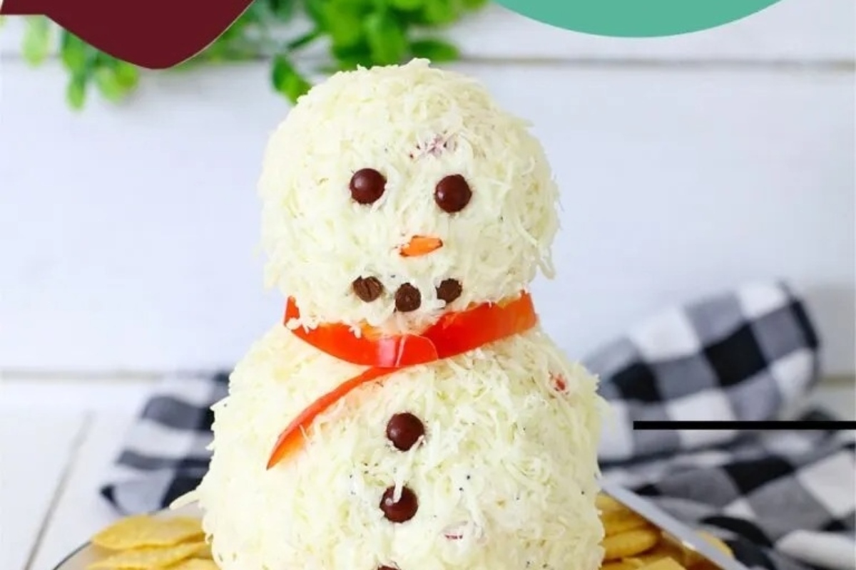 A festive cheese ball snowman with crackers on a plate.