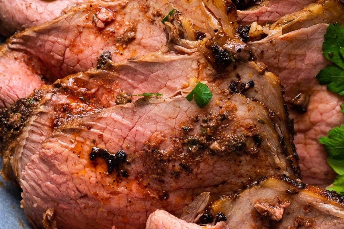 A plate of roasted lamb with Christmas herbs on it.