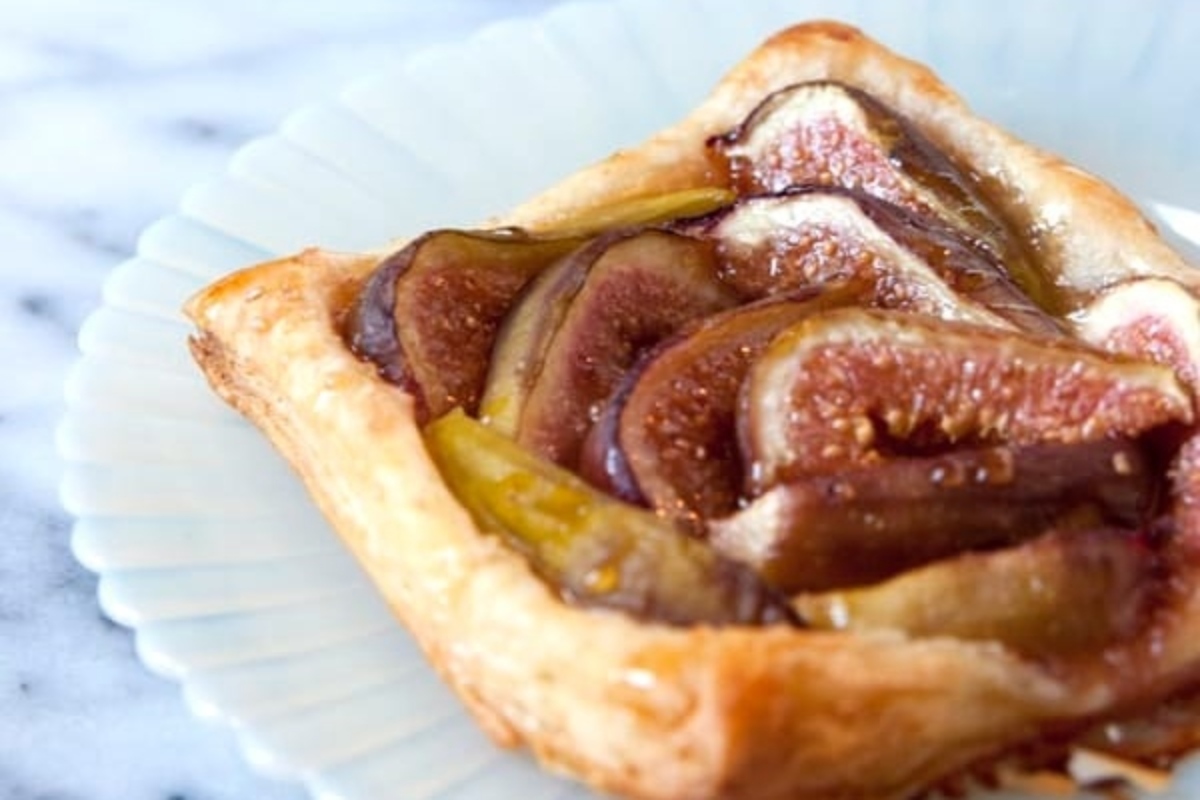         Recipe for a delicious fig tart garnished with fresh figs on a plate.