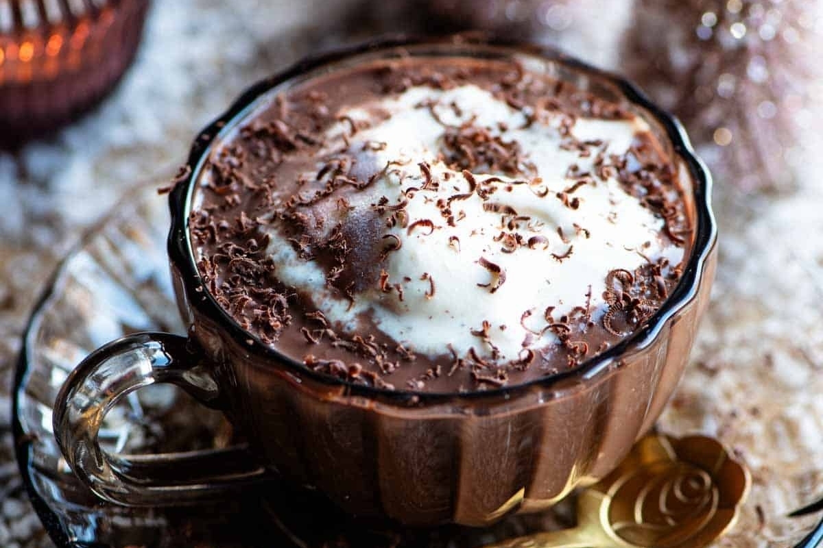 A steaming cup of hot chocolate with whipped cream on top.
