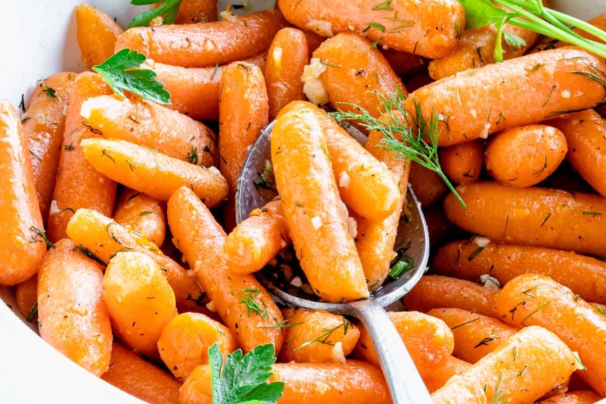 Carrots in a white bowl with a spoon, perfect as a side dish for Christmas.