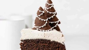 A slice of chocolate cake with a festive christmas tree on top, perfect for celebrating the holidays.