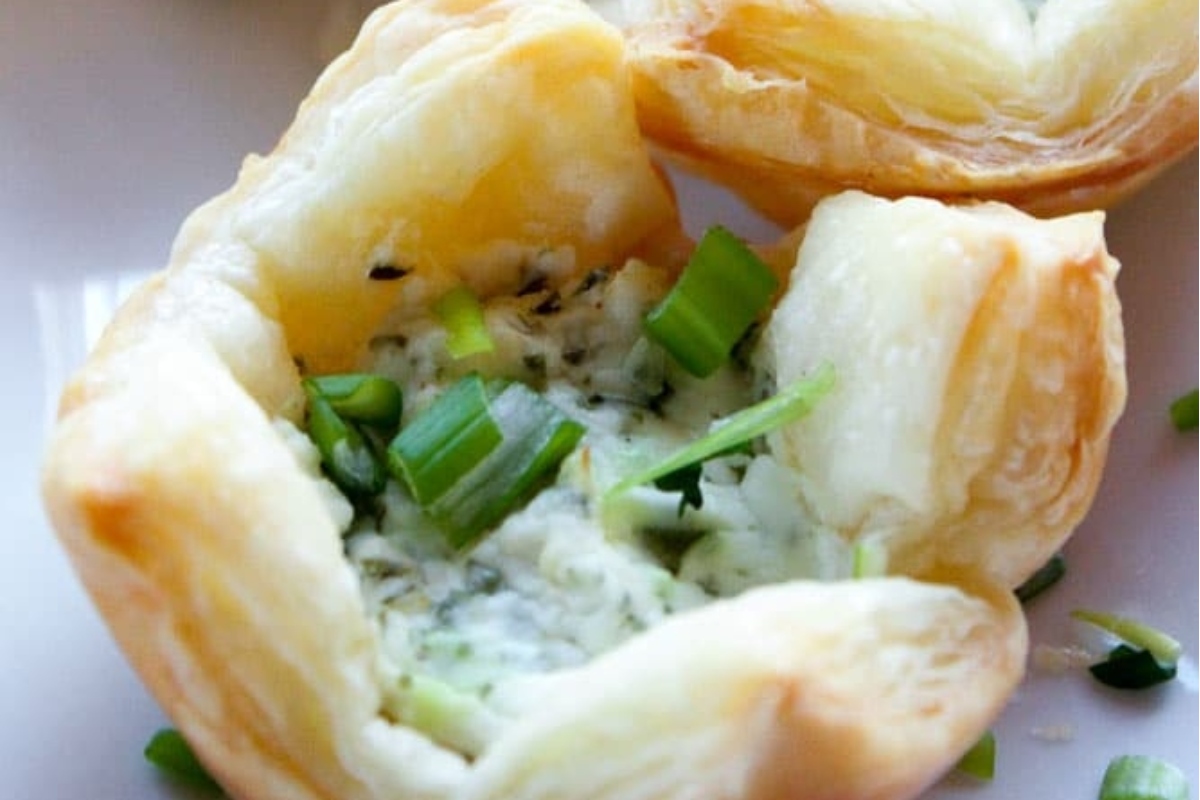 A white plate with small puff pastry shells filled with goat cheese and chives, perfect as appetizers.