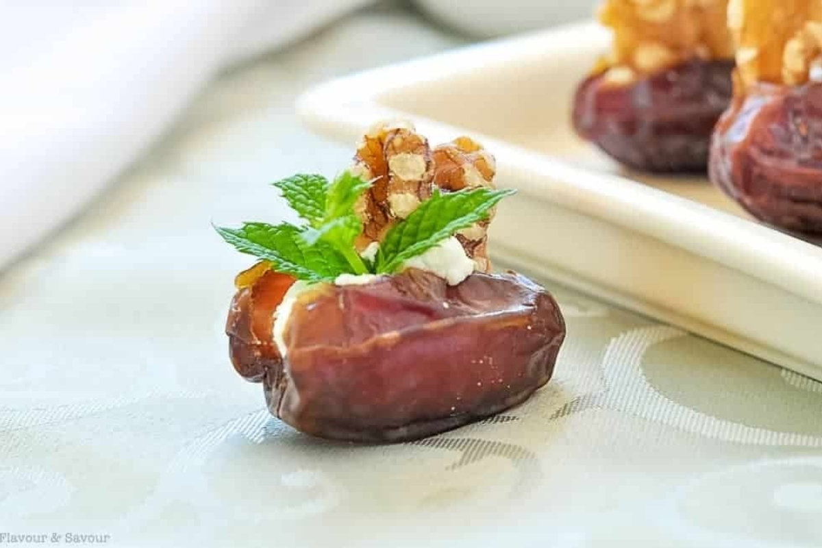 A plate of dates with walnuts and mint leaves, perfect for Christmas appetizers.