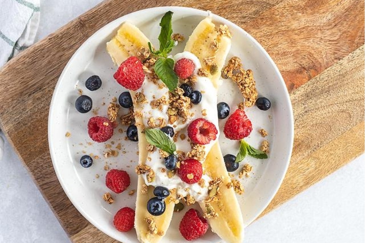An easy breakfast recipe featuring a plate of granola and berries on a wooden cutting board.