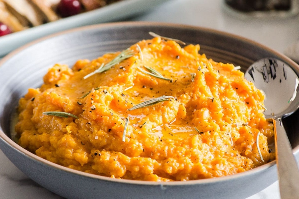 A festive side dish for Christmas, featuring a bowl of sweet potato mashed potatoes with a hint of rosemary.