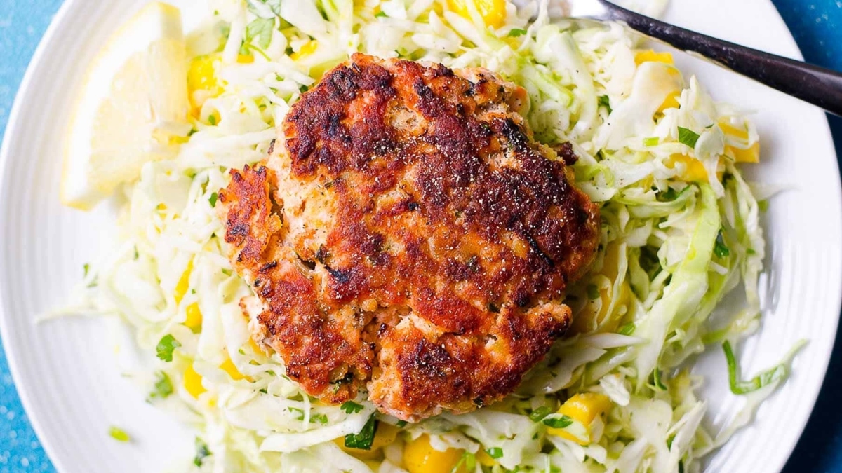A plate with a crab cake and coleslaw, perfect for dinners.