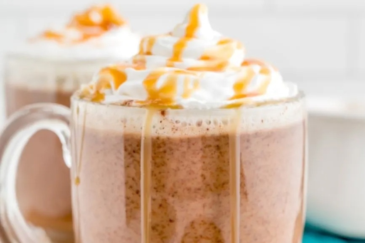 Two mugs of cocoa with caramel and whipped cream.