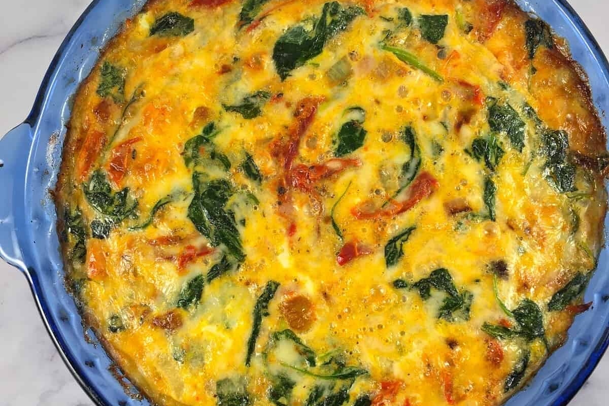A healthy and high protein breakfast - a blue dish with a spinach and tomato quiche.