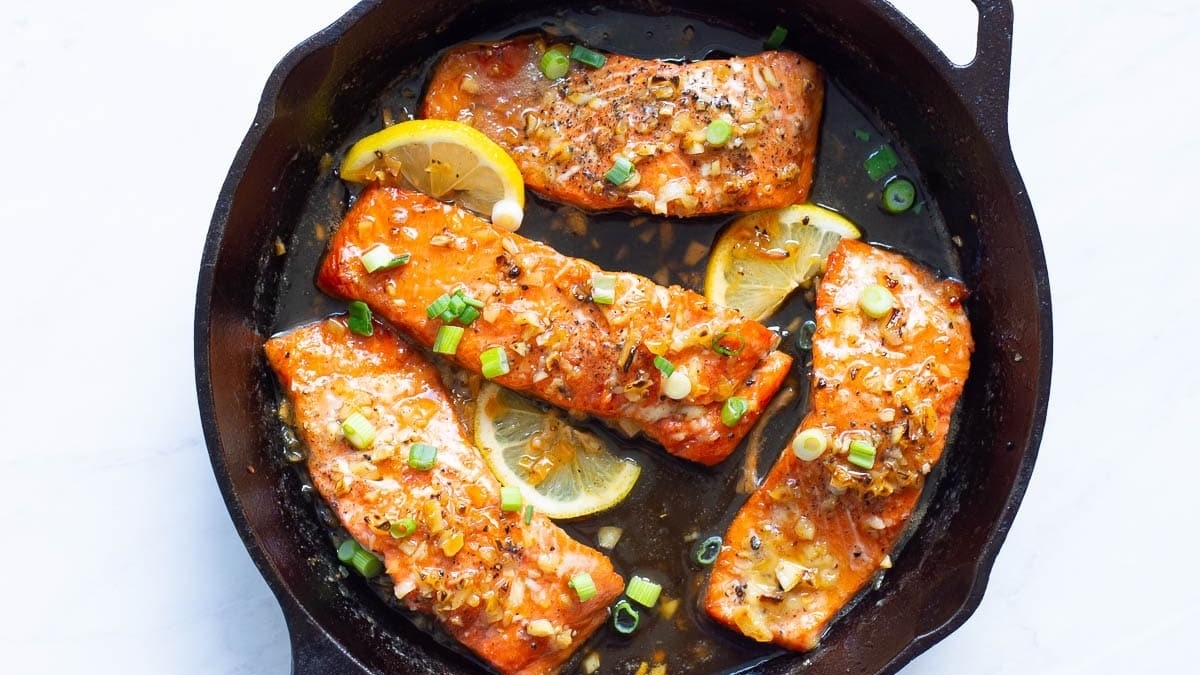 22 Salmon Dinners Your Family Will Love 10 Salmon fillets in a skillet with lemon slices, perfect for a quick and delicious salmon dinner.