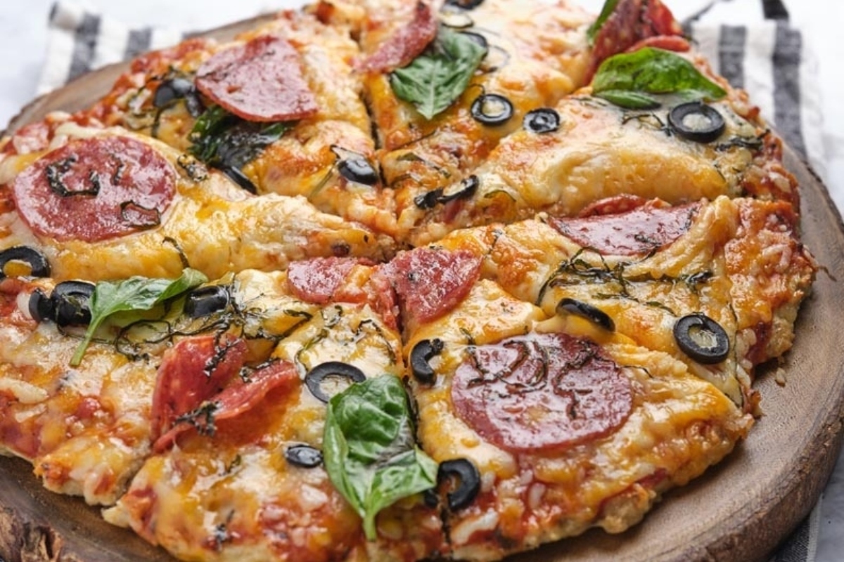 A low carb dinner option, this pizza features pepperoni and olives on a wooden plate.