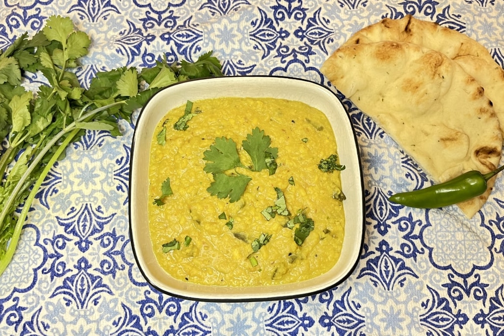 Explore a tantalizing bowl of yellow curry, perfectly paired with fluffy naan on a vibrant blue tablecloth. Dive into the world of delicious curry recipes!