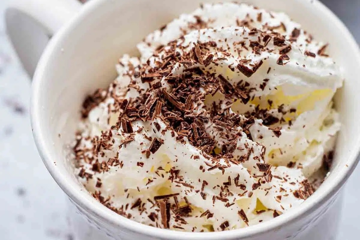 A decadent mug cake topped with whipped cream and chocolate sprinkles.