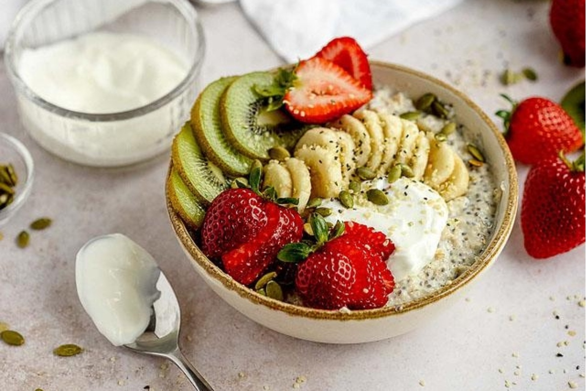 An easy breakfast recipe featuring a bowl of oatmeal topped with kiwi, strawberries, and yogurt.