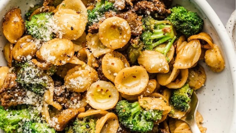 A savory recipe featuring a bowl of pasta with deliciously cooked broccoli, meat, and a generous sprinkle of Parmesan cheese.