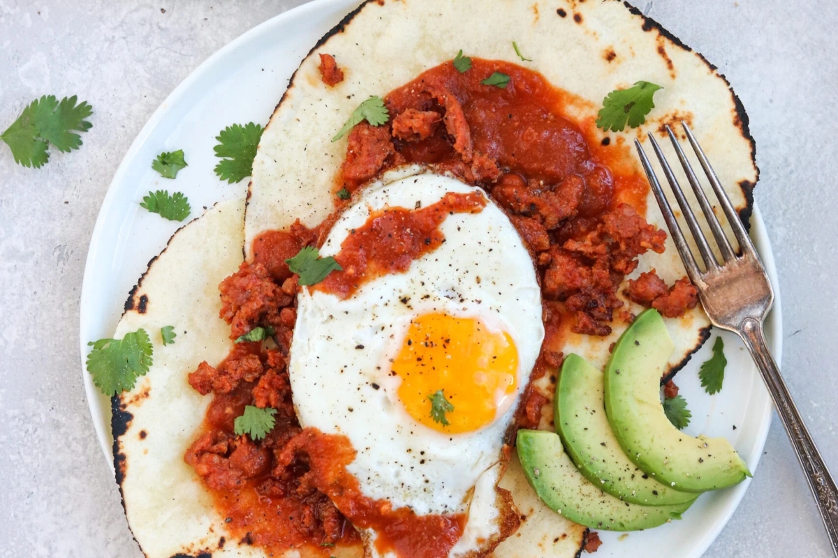 A healthy breakfast plate of tacos topped with a fried egg, providing a high protein option.