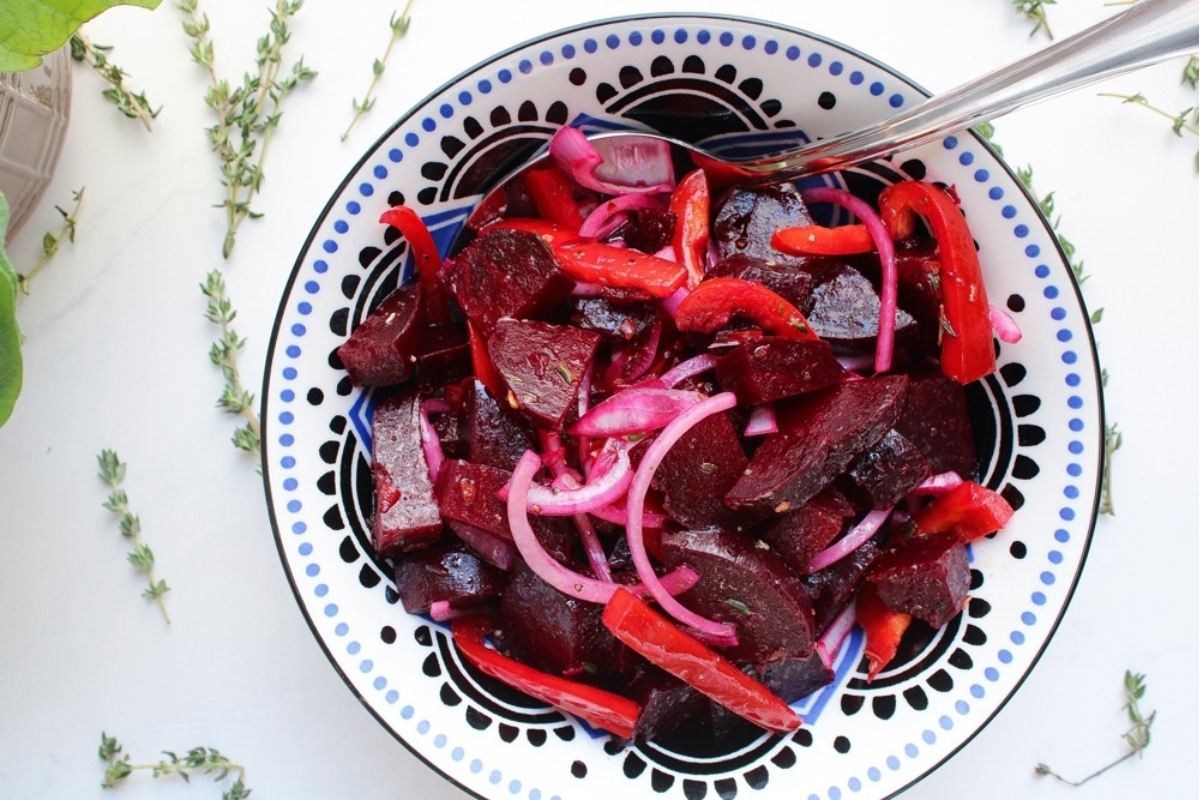 A bowl of beets and onions with a spoon, perfect for making delicious beet recipes.