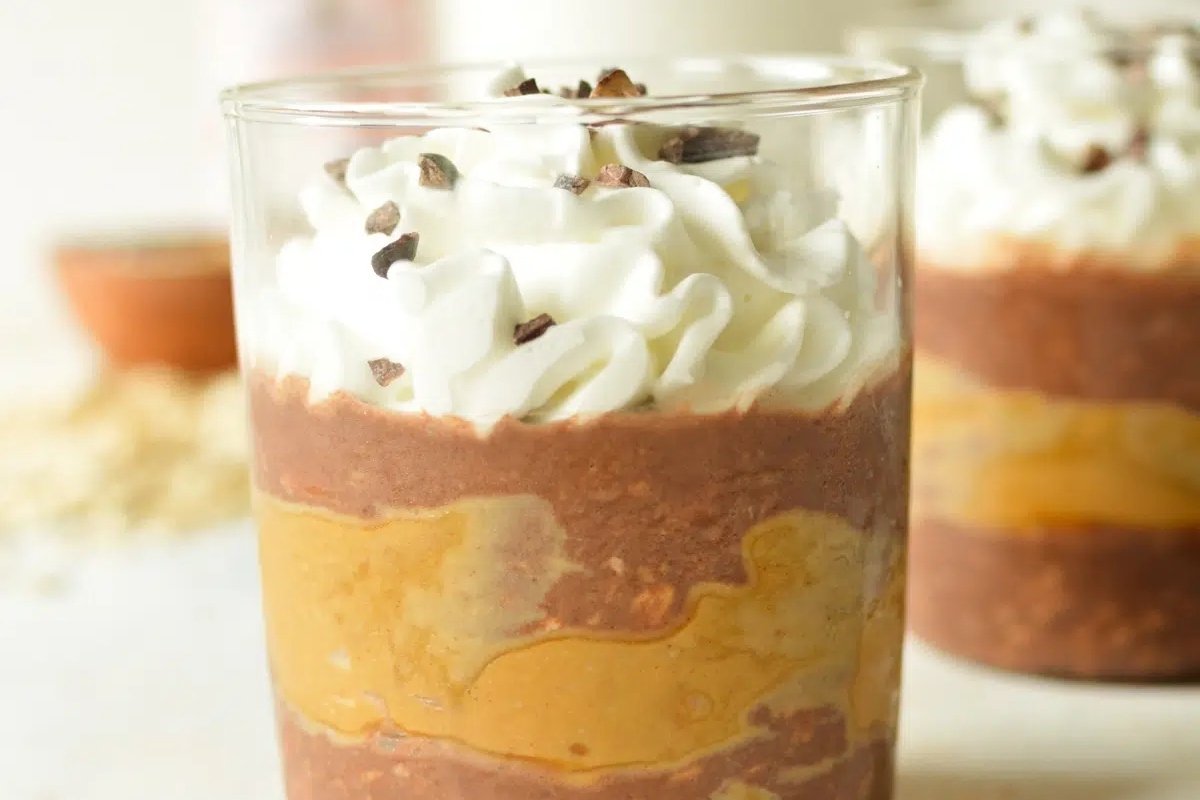 A cup of chocolate pudding with whipped cream and chocolate chips, perfect for a indulgent treat.
