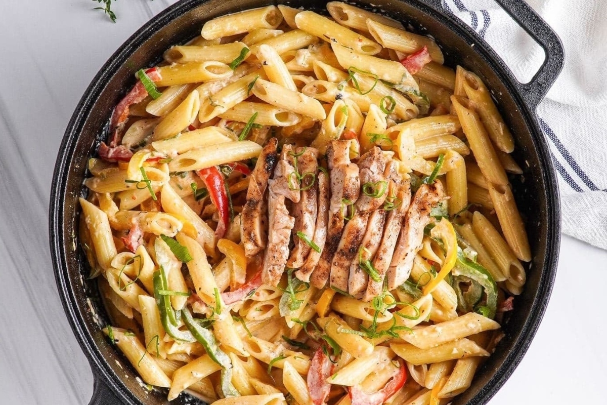 An inexpensive family dinner, filled with love, featuring a skillet full of pasta with chicken and vegetables.