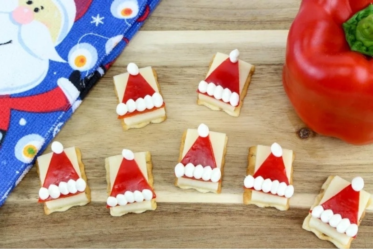 Themed Santa hat crackers arranged on a cutting board.