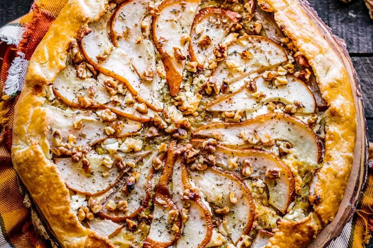 An appetizing pie with pears and walnuts on top.