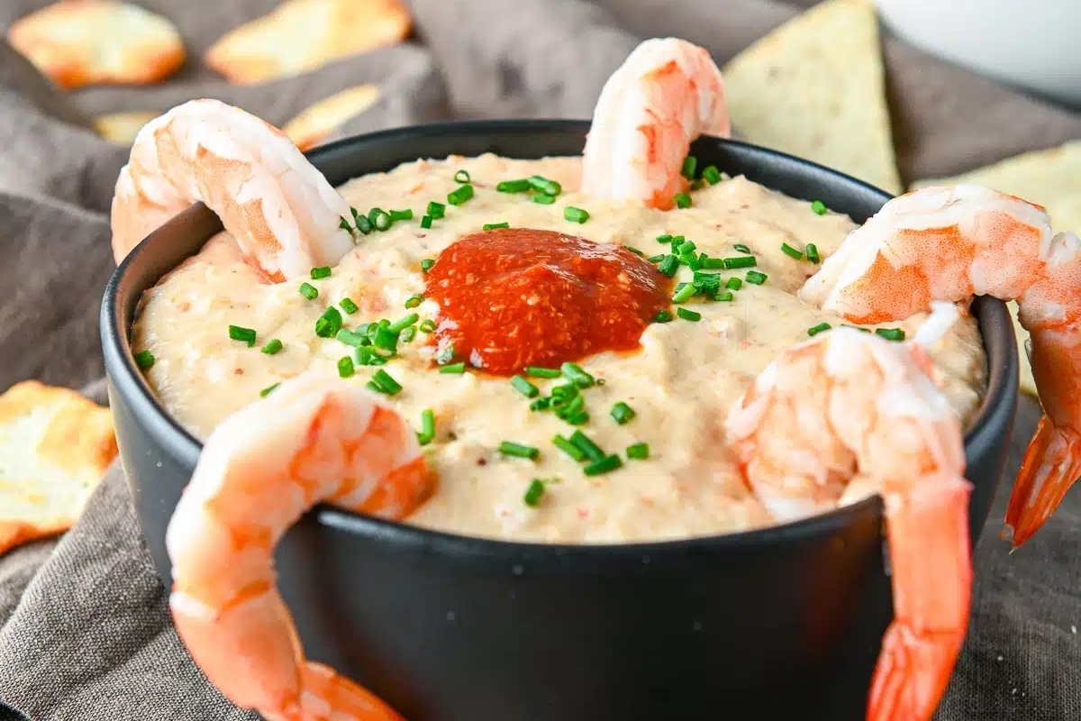 Shrimp dip made with cream cheese, served in a bowl with crackers.