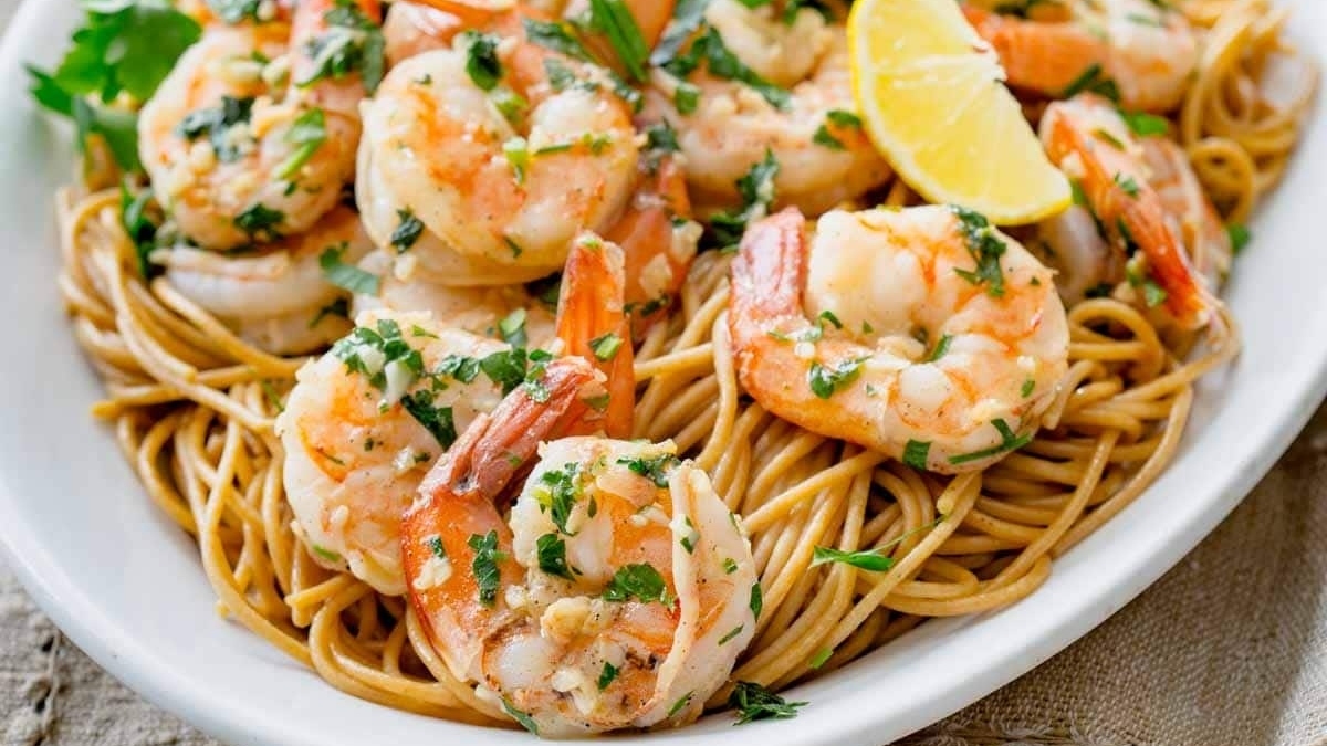 A Shrimp Dinner featuring a plate of pasta with shrimp and lemon wedges.