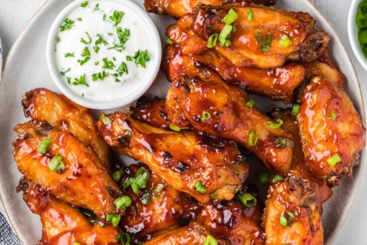Bbq chicken wings on a plate with dipping sauce.