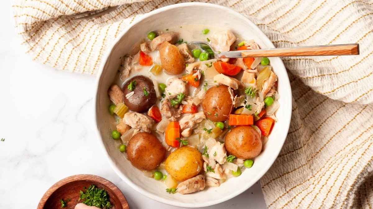Slow Cooker chicken stew in a white bowl with potatoes and carrots.