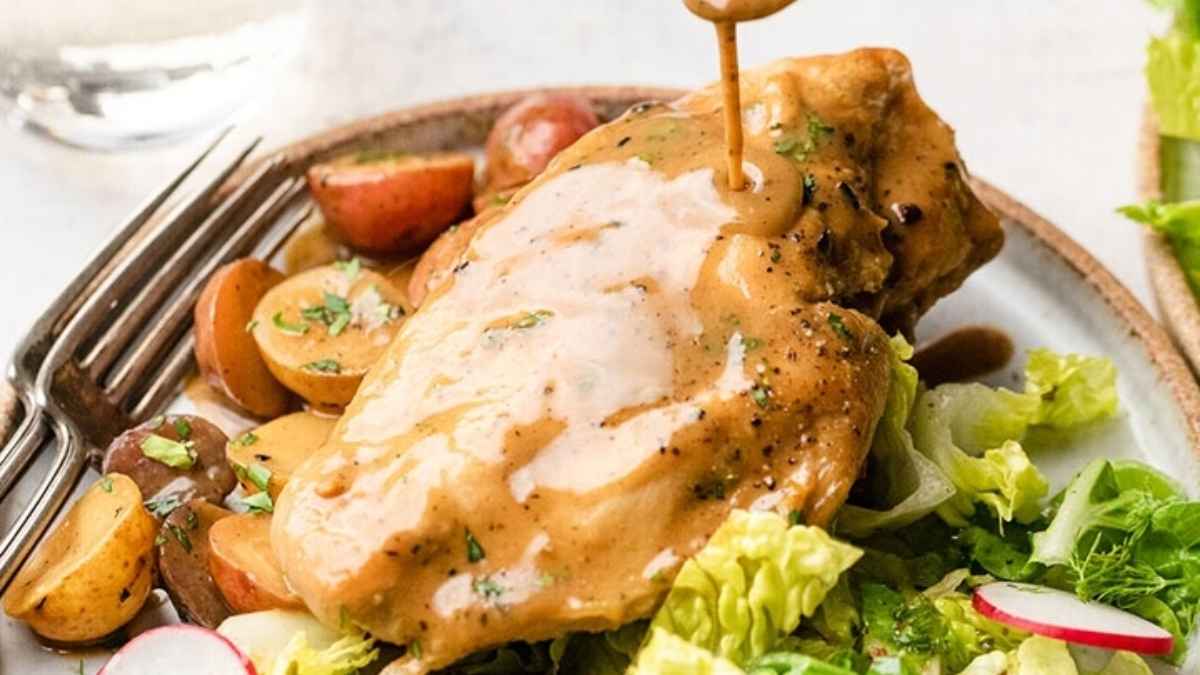 A slow cooker dinner featuring tender chicken being served with a flavorful sauce poured over it.