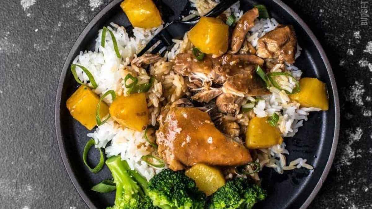 Slow Cooker Hawaiian chicken with pineapple and broccoli on a black plate.