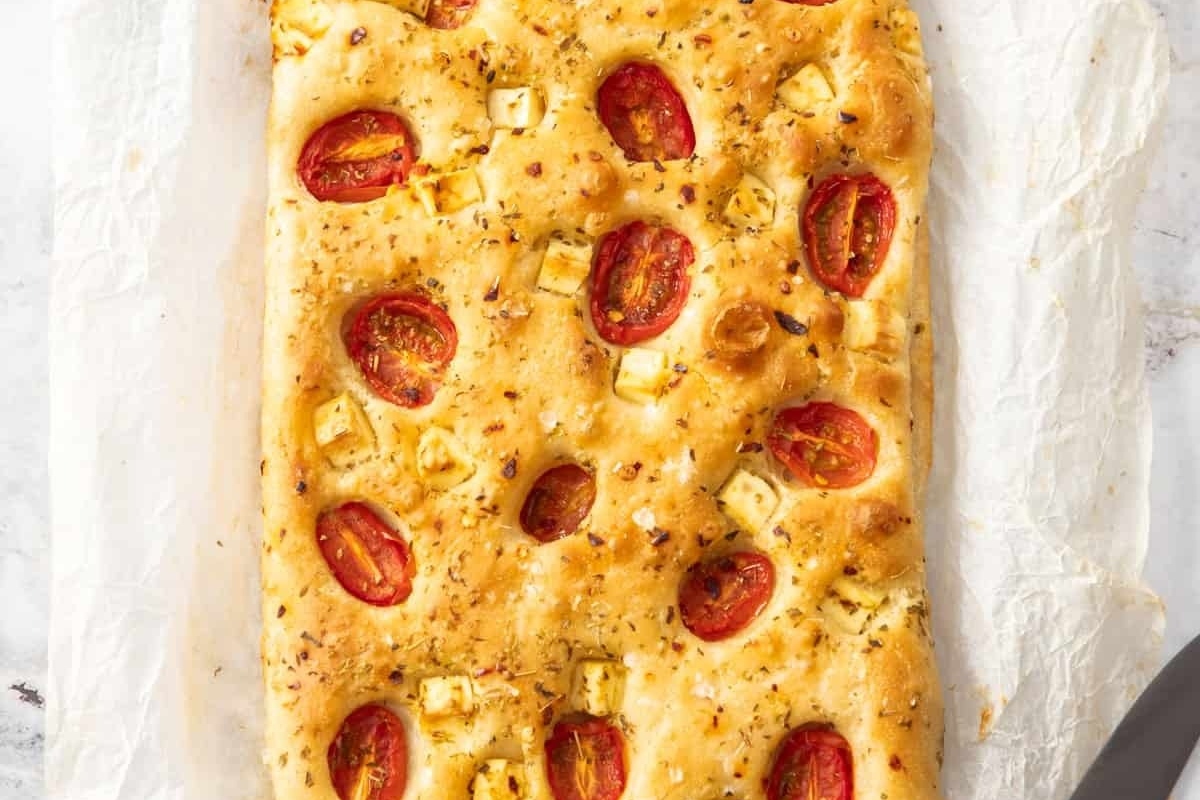 A focaccia pizza recipe with tomatoes and cheese on a baking sheet.