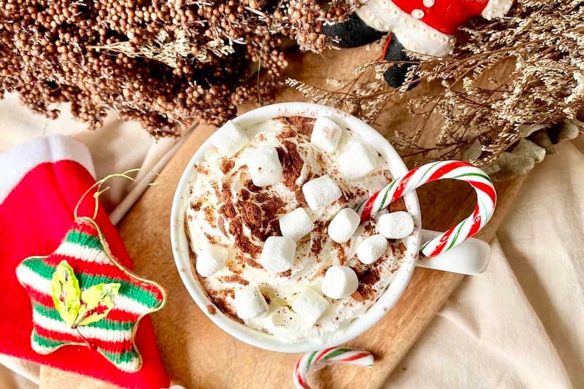 A steaming cup of hot cocoa with marshmallows and candy canes.