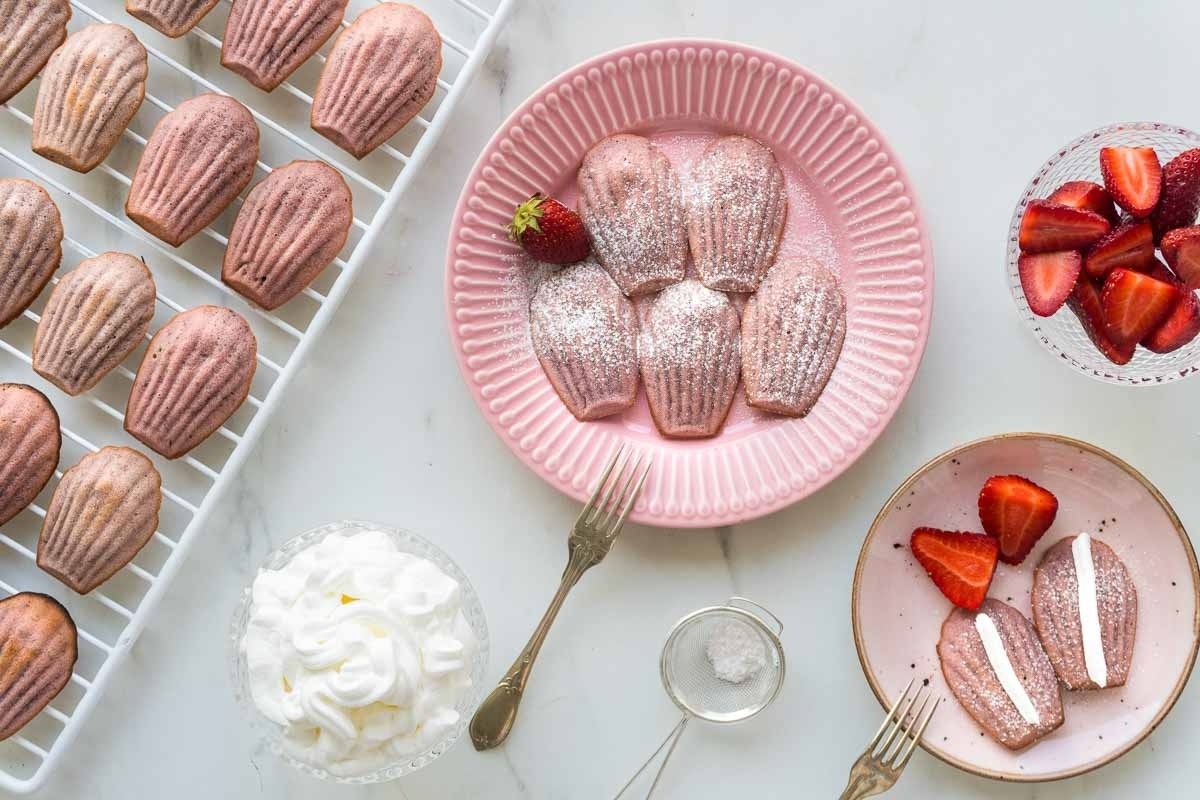 Valentine's Day strawberry macarons on a plate with whipped cream and strawberries.