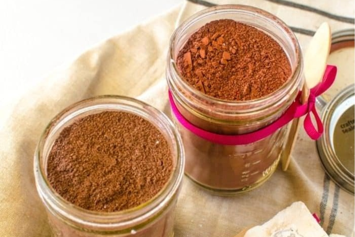 Two jars of cocoa powder for hot chocolate on a table.