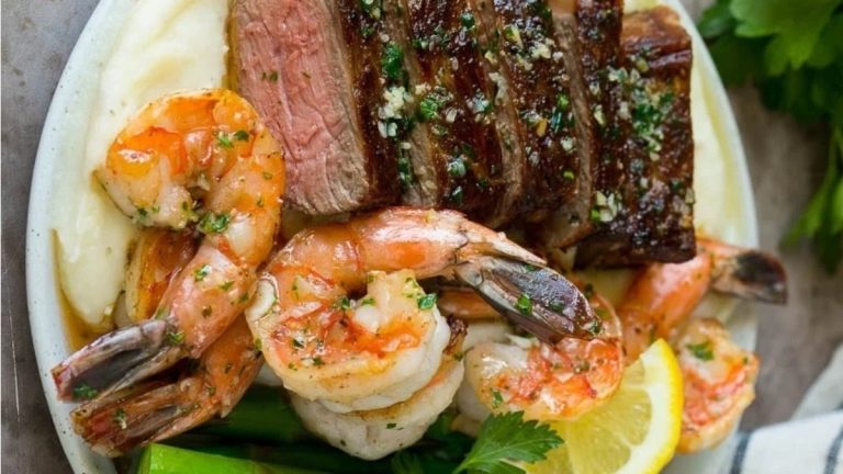 A delectable combination of steak and shrimp, served alongside creamy mashed potatoes, perfect for a romantic Valentine's Day dinner.