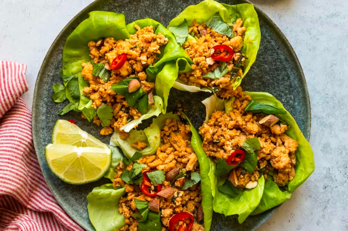 Thai lettuce wraps on a plate with lime wedges, perfect for inexpensive family dinners that everyone will love.