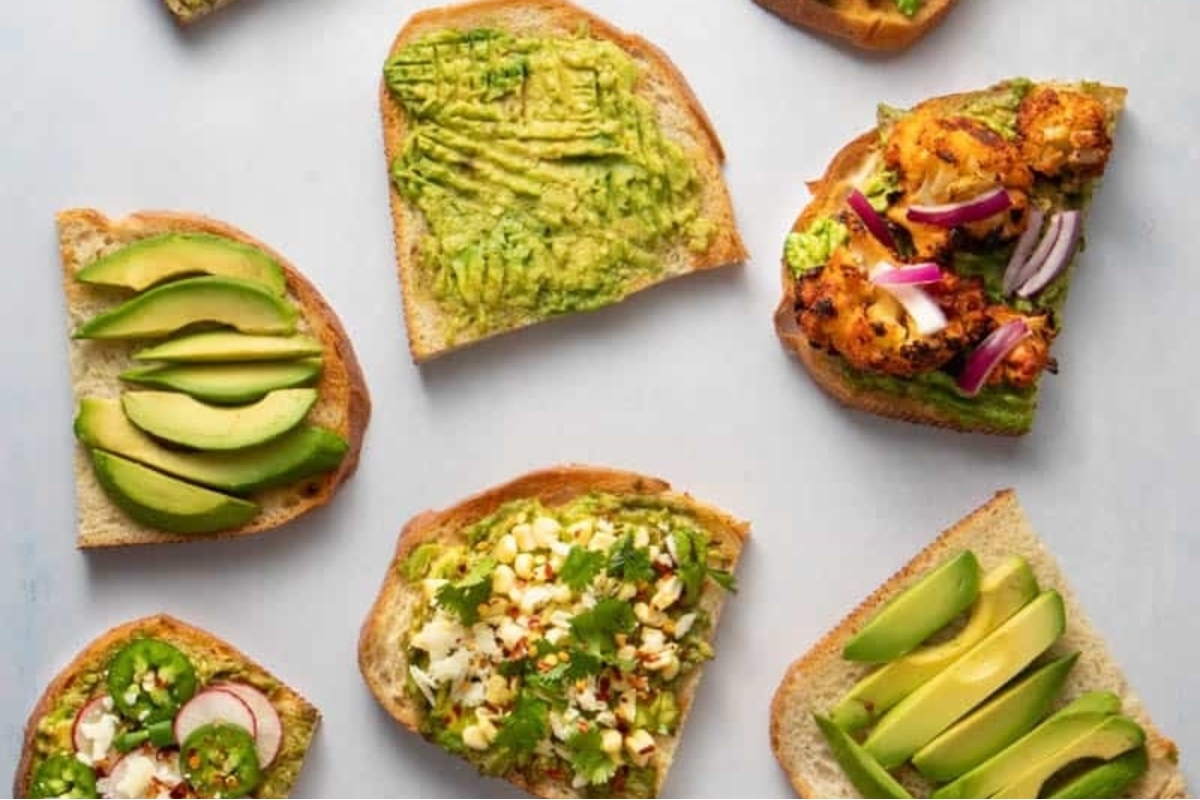 A variety of avocado toasts, perfect for breakfast, are arranged on a white surface.