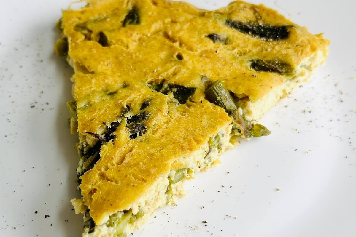 A healthy slice of quiche on a white plate.