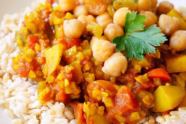 A delicious curry recipe featuring a plate of flavorful rice, chickpeas, and vegetables.