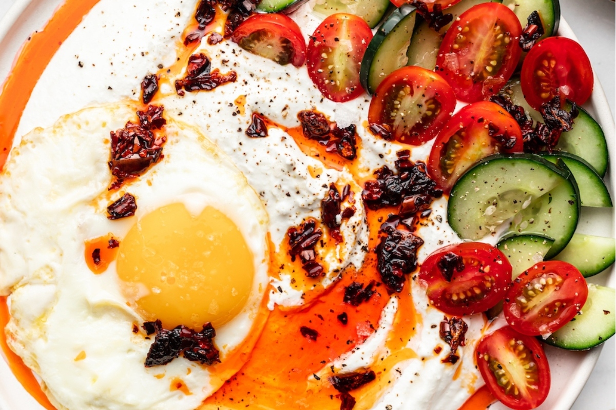 An easy breakfast recipe with a plate of fried egg, tomatoes, and cucumbers.