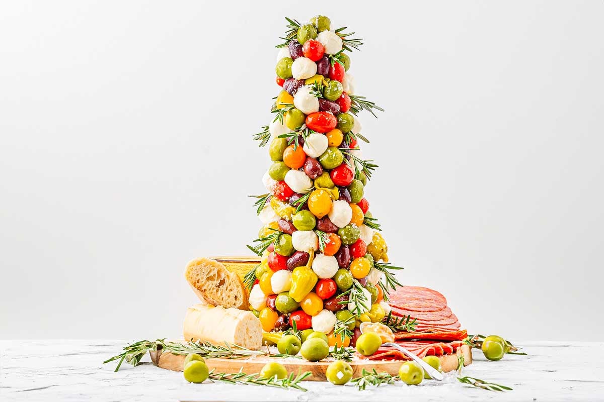 A festive tower of cheese, olives, and meats on a table, perfect for Christmas charcuterie boards.