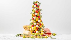 A festive tower of cheese and olives on a Christmas charcuterie board.