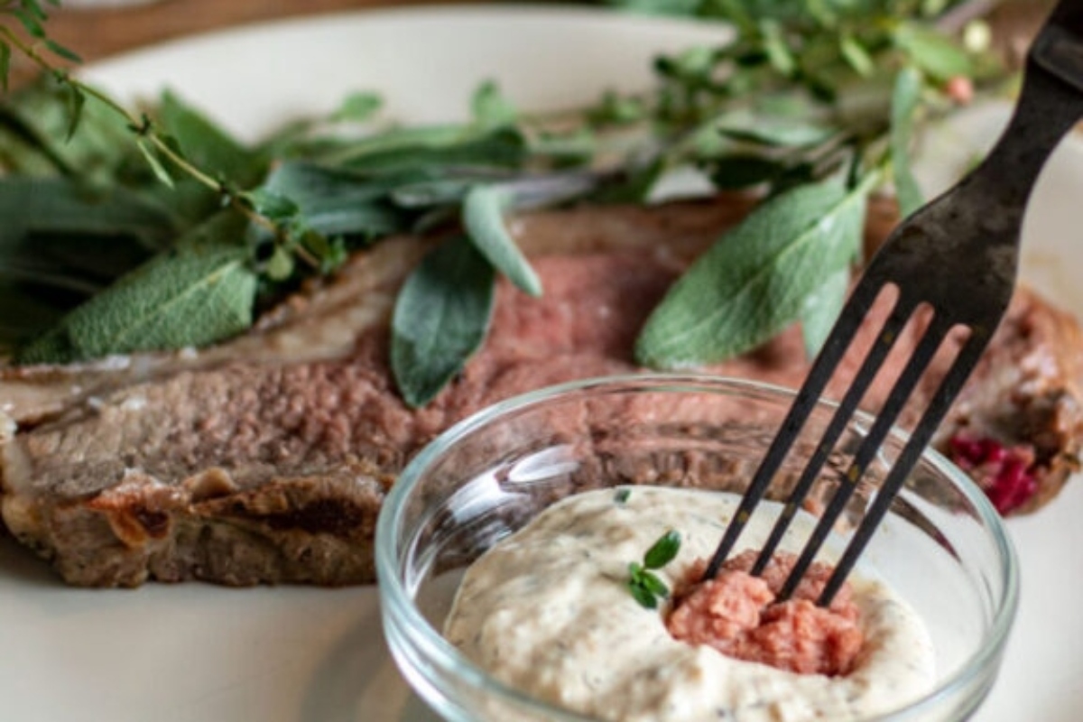 A winter recipe featuring a mouthwatering beef steak served on a plate, topped with creamy sour cream and fragrant sage.