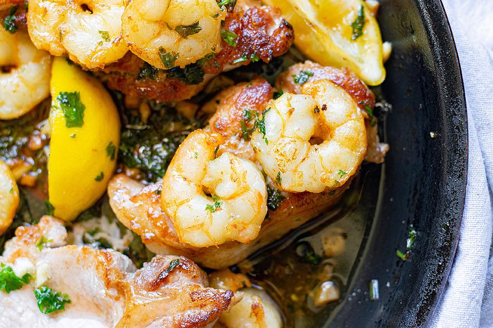 Surf and turf - Shrimp with lemon and herbs in a skillet.