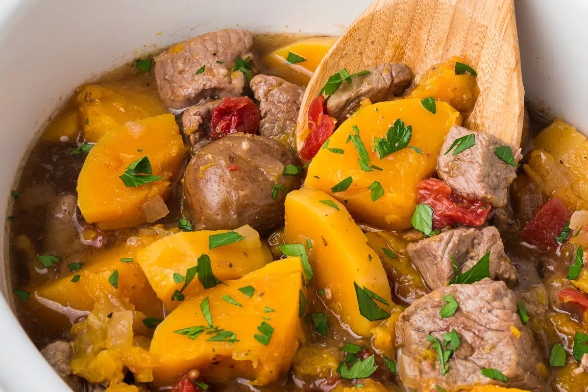 Slow cooker stew with meat and potatoes in a white bowl.
