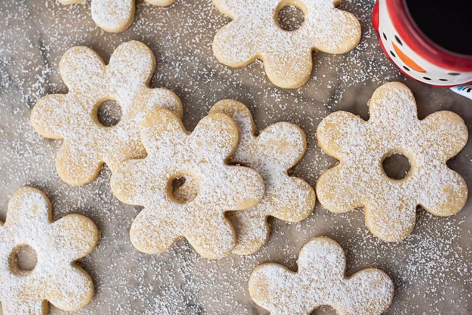 Christmas sugar cookies perfect for the holiday season, dusted with powdered sugar. Enjoy them with a cup of coffee.