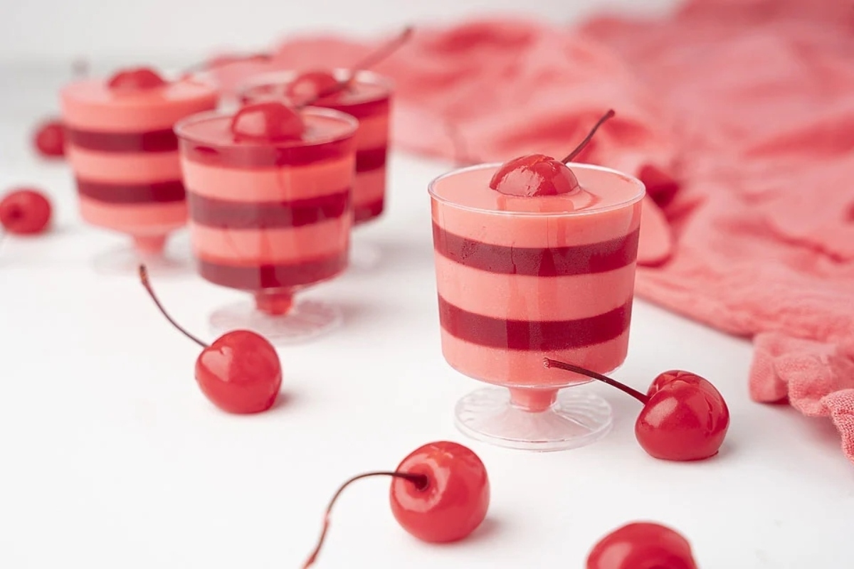 A group of red and white striped cups with cherries in them, perfect for Valentine's Day desserts.